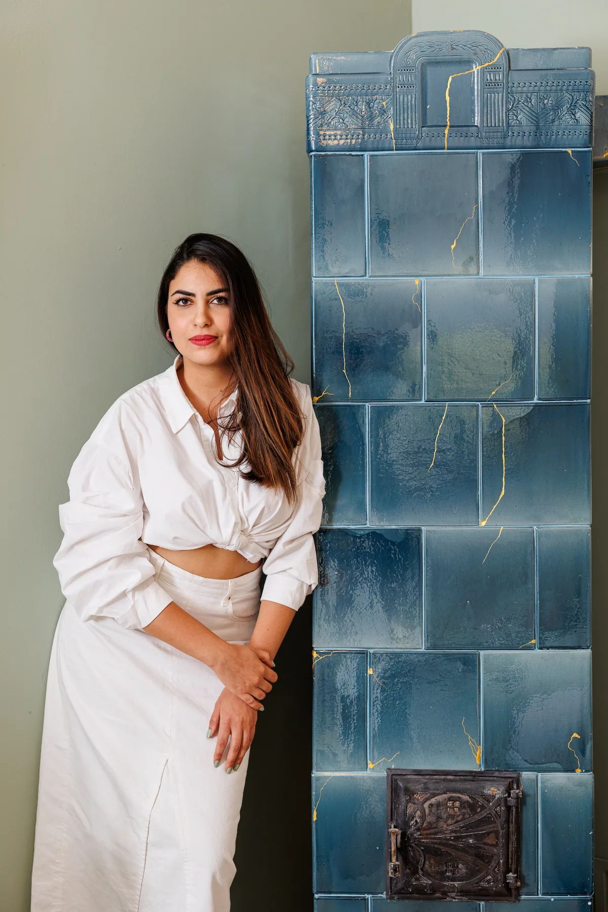 Lina Ben Khalifa beside the blue tiled stove in an LBK interior