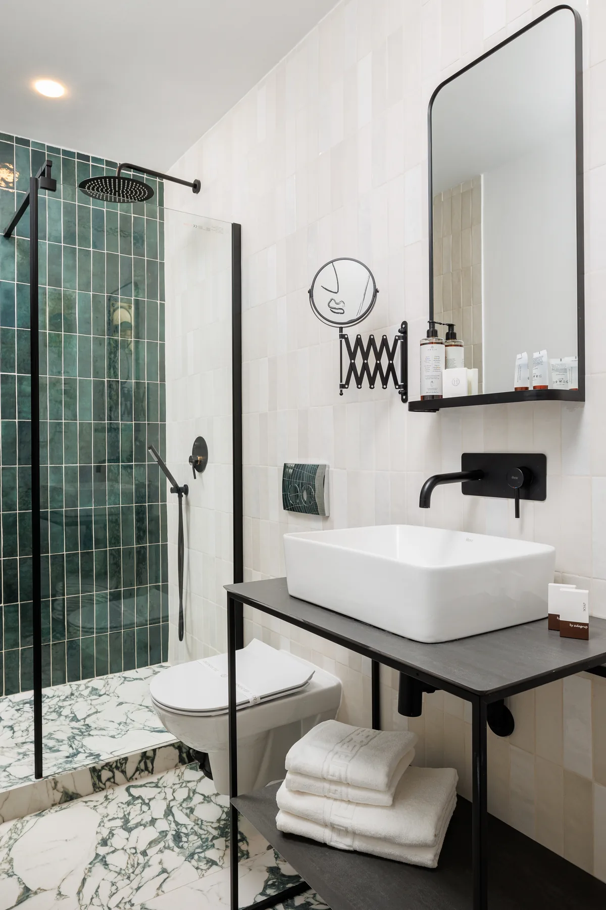 Bathroom with a white basin, green shower tiles and a wall mirror