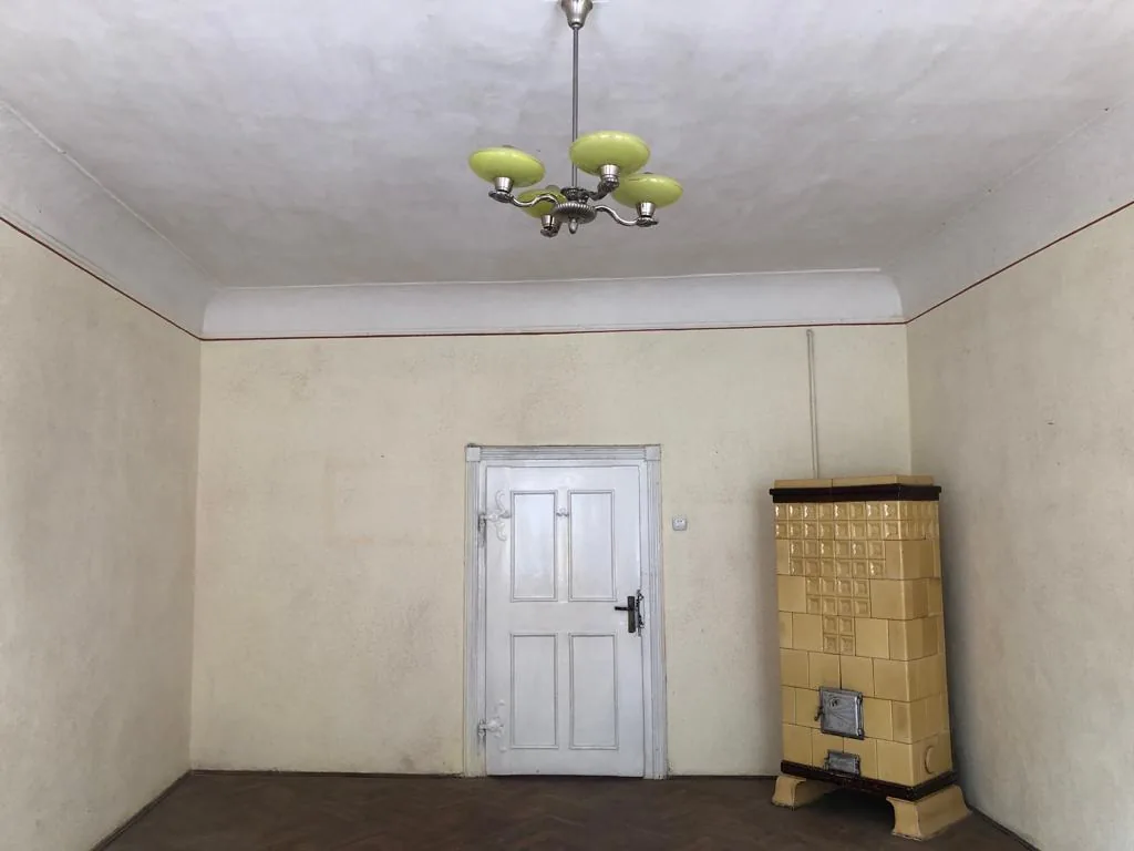 Original room with a white door and a yellow tiled stove