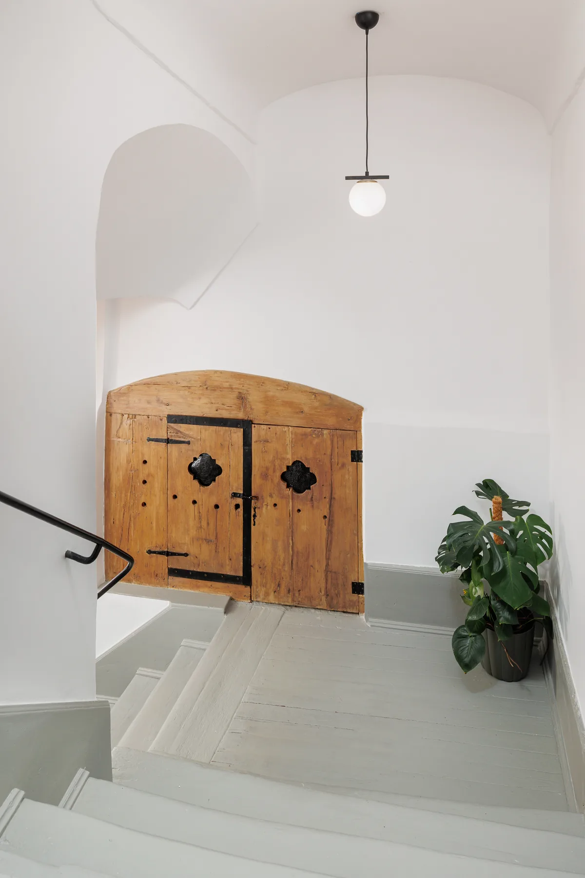 White stairs leading to an arched timber cupboard